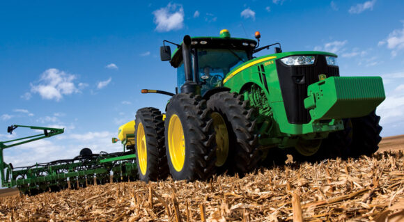 JD tractor harvesting crops on sunny day