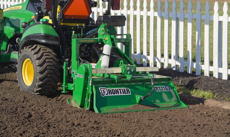 John Deere Frontier RT1142 rotary tiller attached to lawn tractor in garden soil