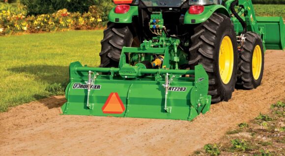 John Deere tractor operating a Frontier RT2283 rotary tiller to prepare soil.