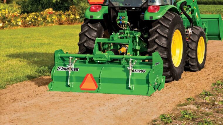 John Deere tractor operating a Frontier RT2283 rotary tiller to prepare soil.