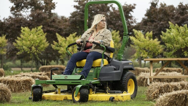 Woman driving a John Deere 530M zero-turn mower