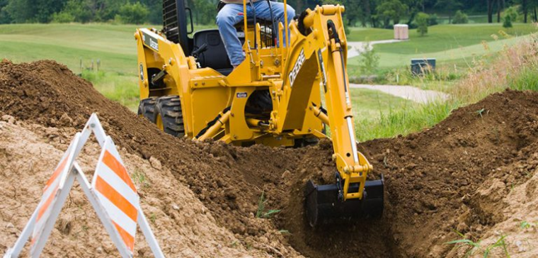 The John Deere BH Model Backhoe digging on a construction site.