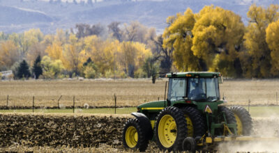 Fort Collins, Colorado, USA - October 20, 2012: A farmer in a tractor plowing a field in autumn outside of Fort Collins, Colorado, with Rocky Mountains in the background.