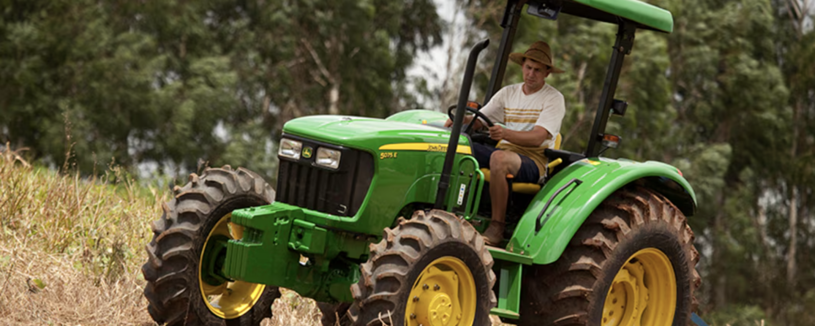 Man riding a green John Deere 5075E tractor