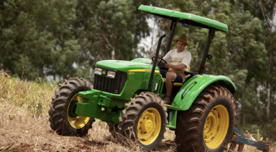 Man riding a green John Deere 5075E tractor