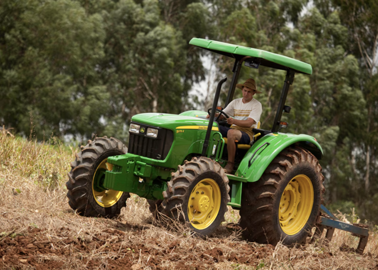 Man riding a green John Deere 5075E tractor