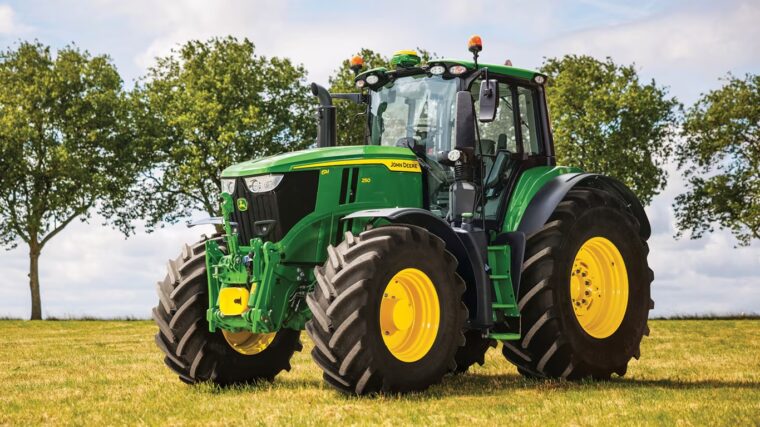 John Deere 6M row crop tractor with dual tires parked in a field.