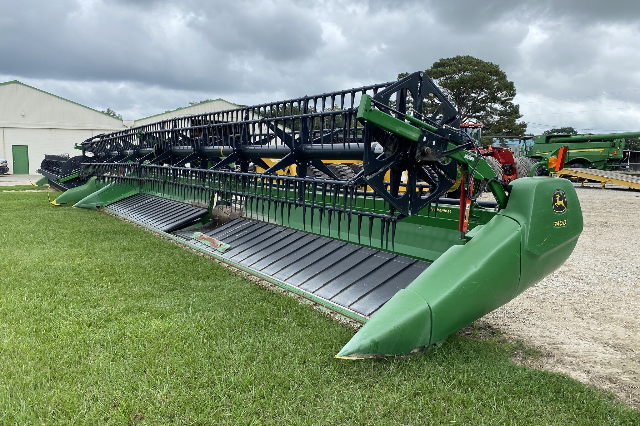 John Deere 740D draper header displayed outdoors at an equipment dealership.