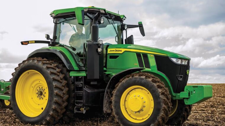 John Deere 7R row crop tractor operating in a harvested field.