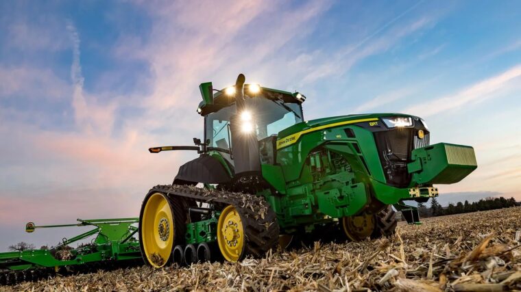 John Deere 8RT row crop tractor with tracks operating in a harvested field.