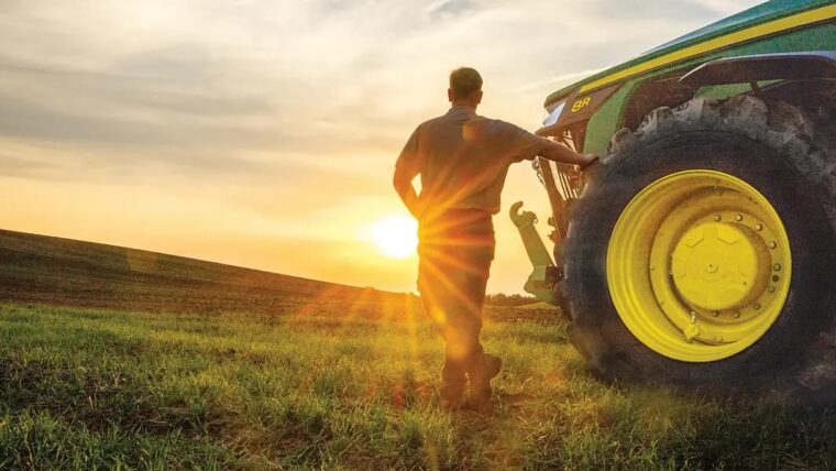 Farmer with John Deere tractor watching the sunset