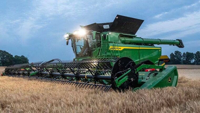 John Deere combine harvesting wheat with a draper header in the field.