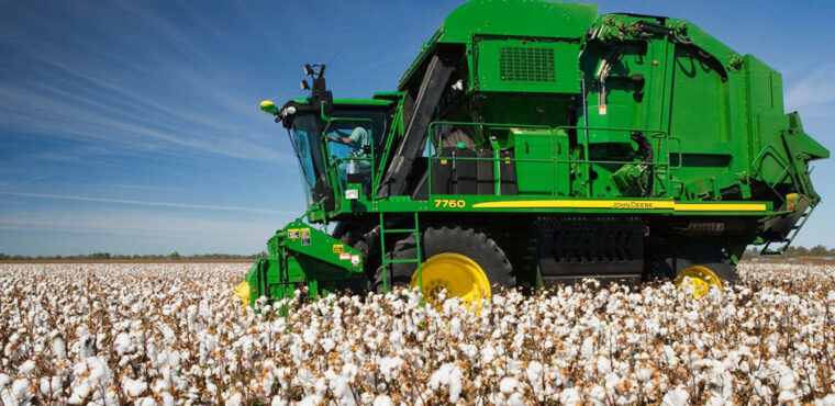 John Deere 7760 cotton picker shown from the side harvesting cotton in a field.