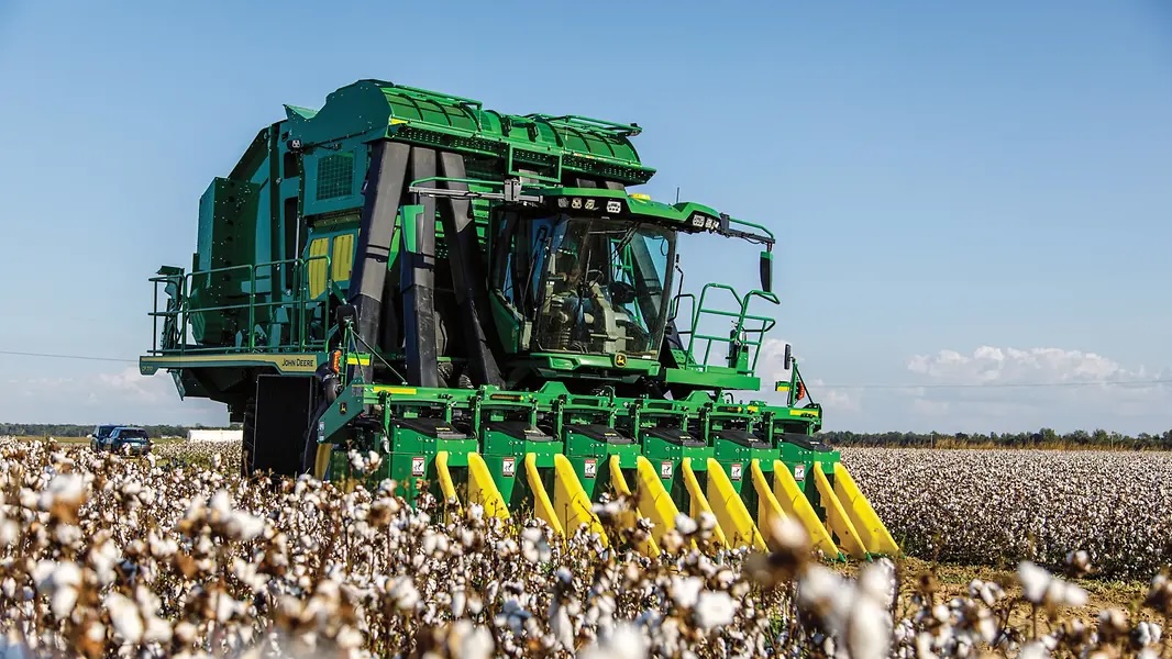 John Deere cotton harvester equipped with a multi-row harvesting header operating in a cotton field.